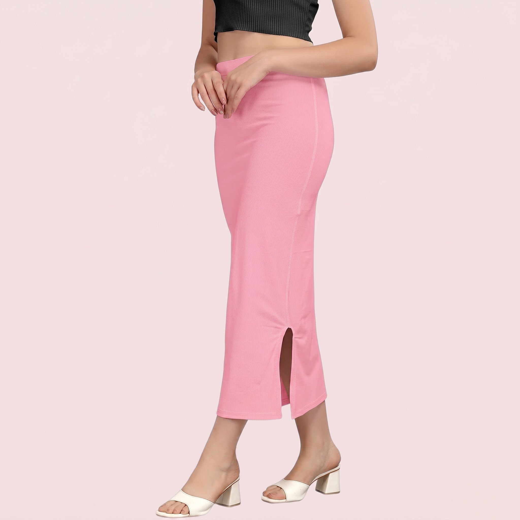 Person wearing a pink slip skirt with a black top on a light pink background