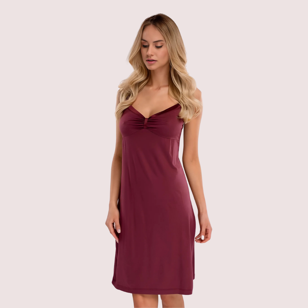 Woman wearing a burgundy dress against a light pink background