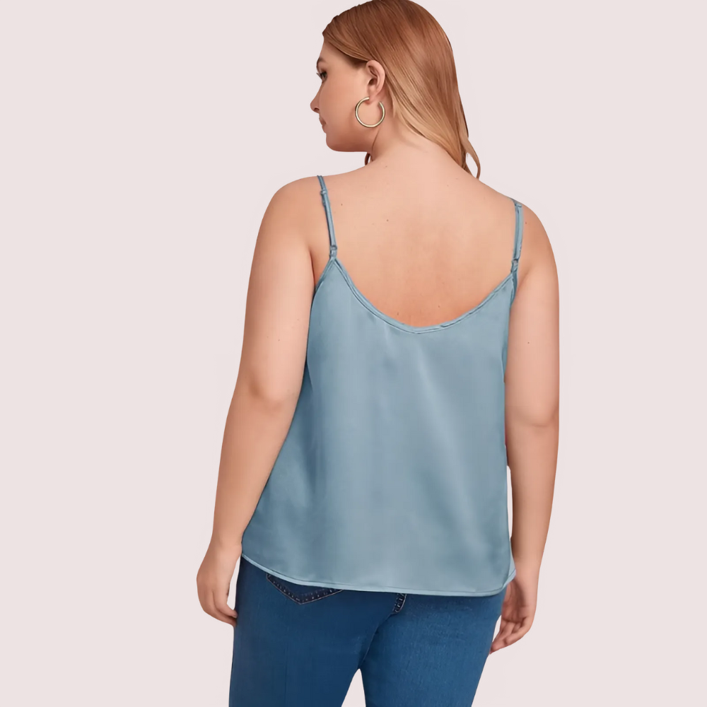 Woman wearing a light blue satin camisole against a plain background