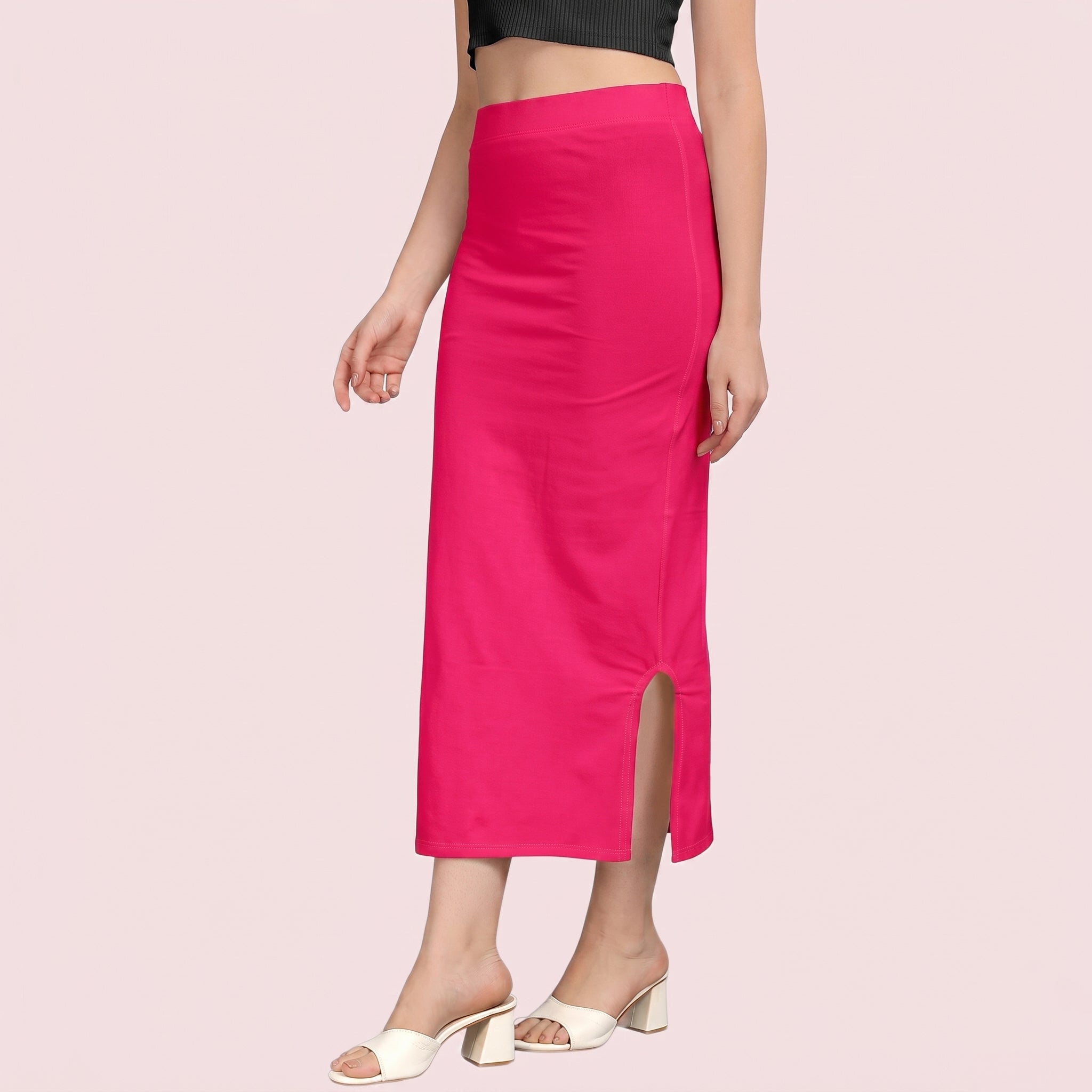 Person wearing a bright pink skirt with a slit on a light pink background