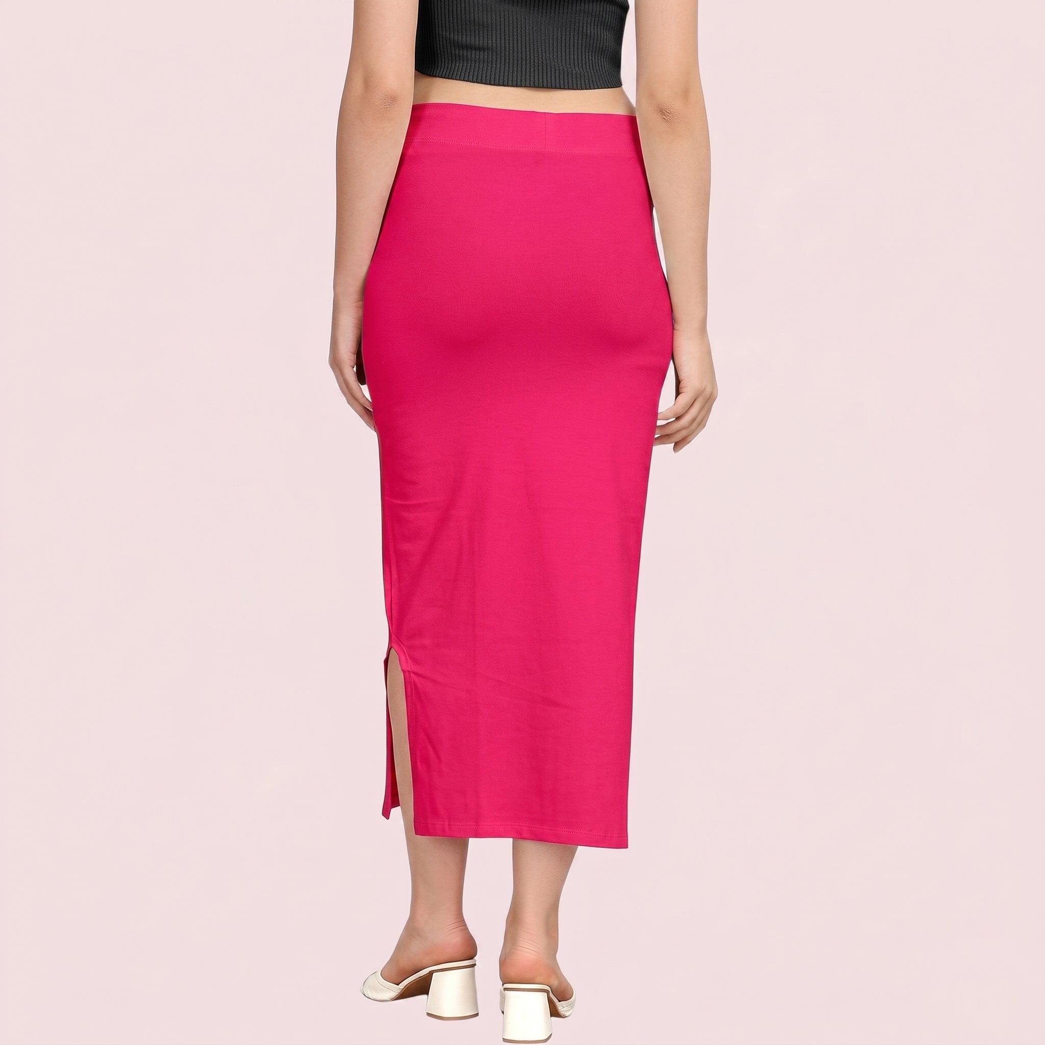 Person wearing a bright pink skirt with a side slit on a light pink background