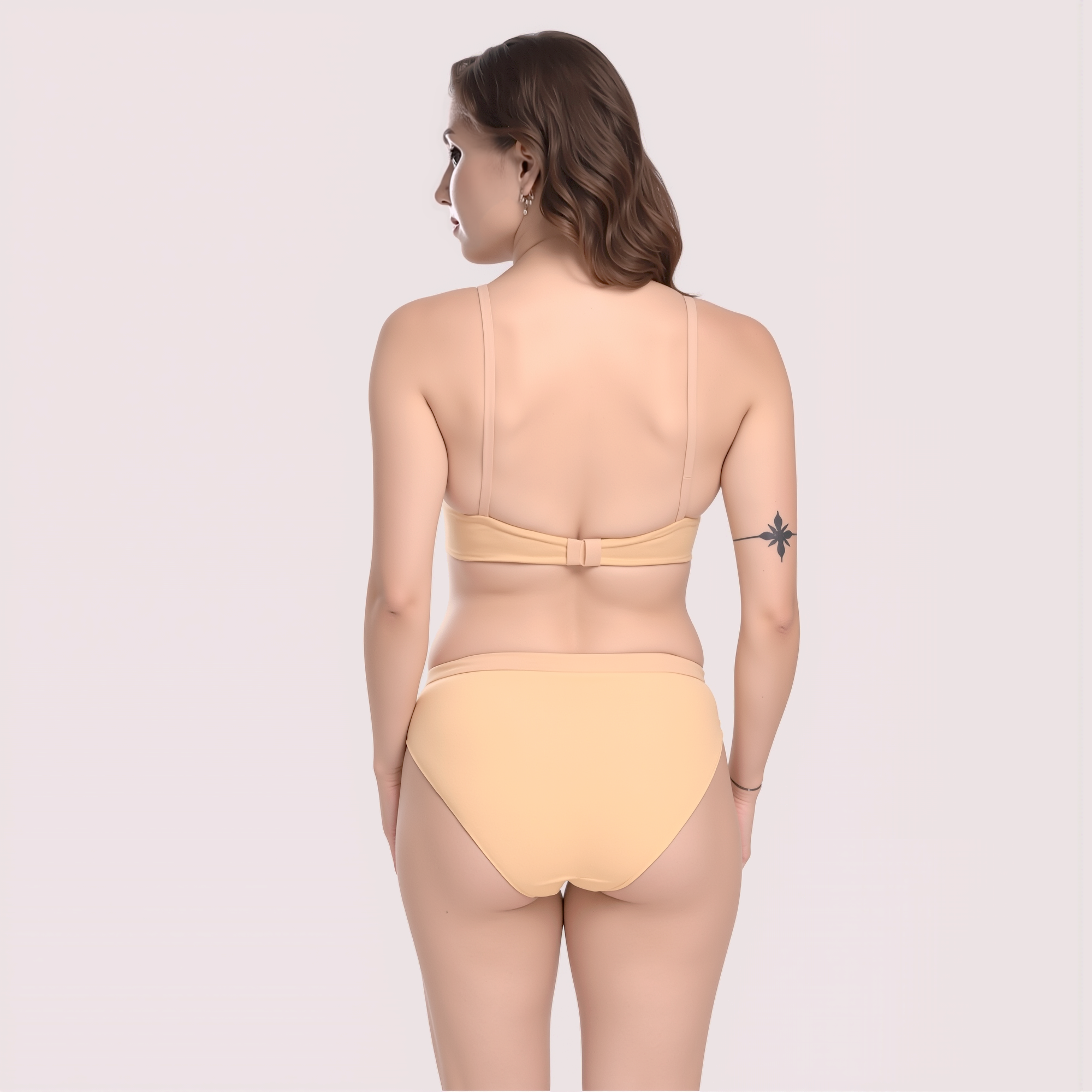 Woman wearing a beige bikini set on a light pink background
