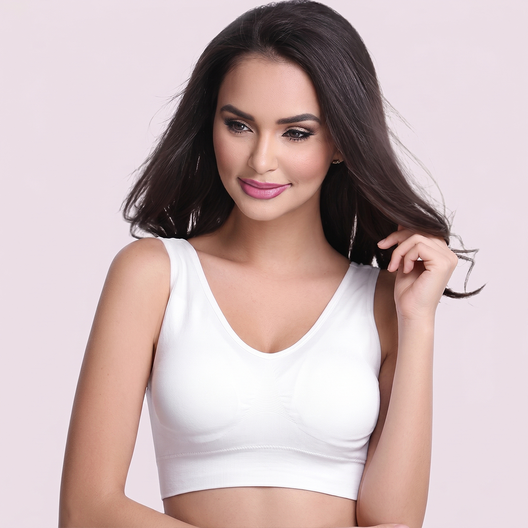 Woman wearing a white tank top against a light pink background