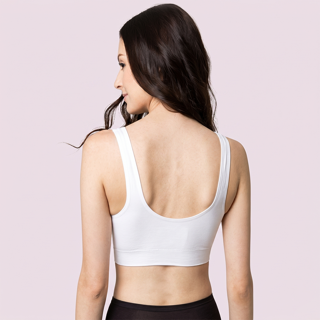 Woman wearing a white sports bra on a light pink background