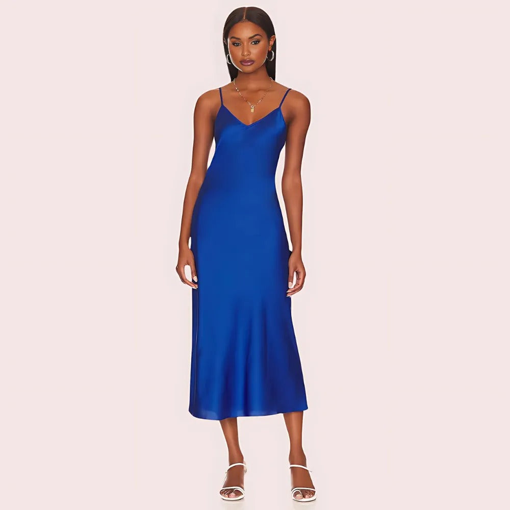 Woman wearing a blue slip dress on a light pink background