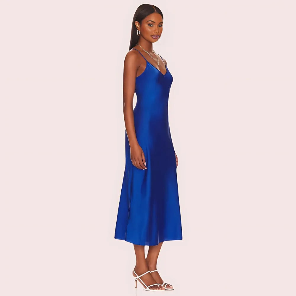 Woman wearing a blue satin slip dress on a light pink background