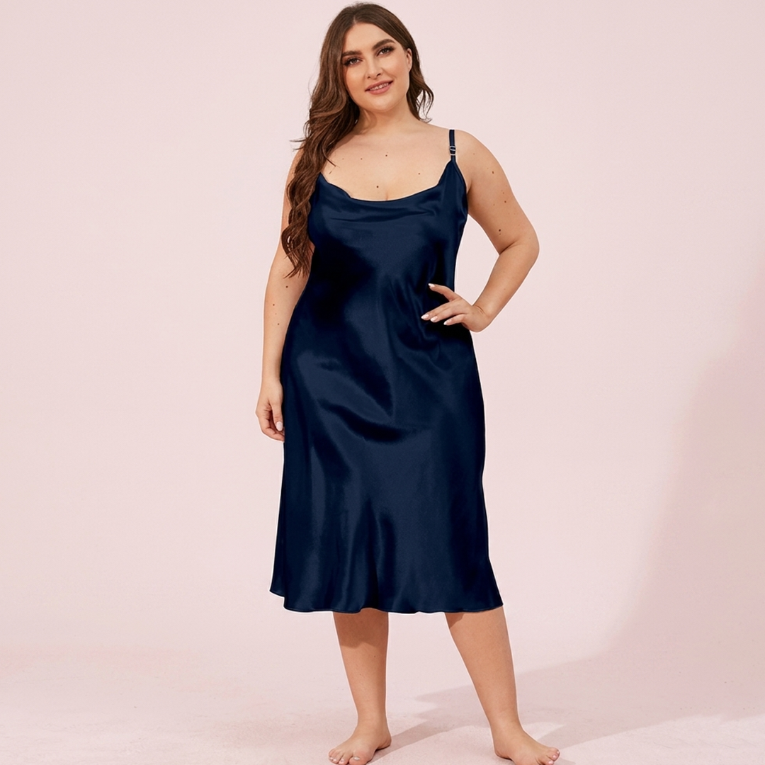 Woman wearing a navy blue slip dress against a pink background