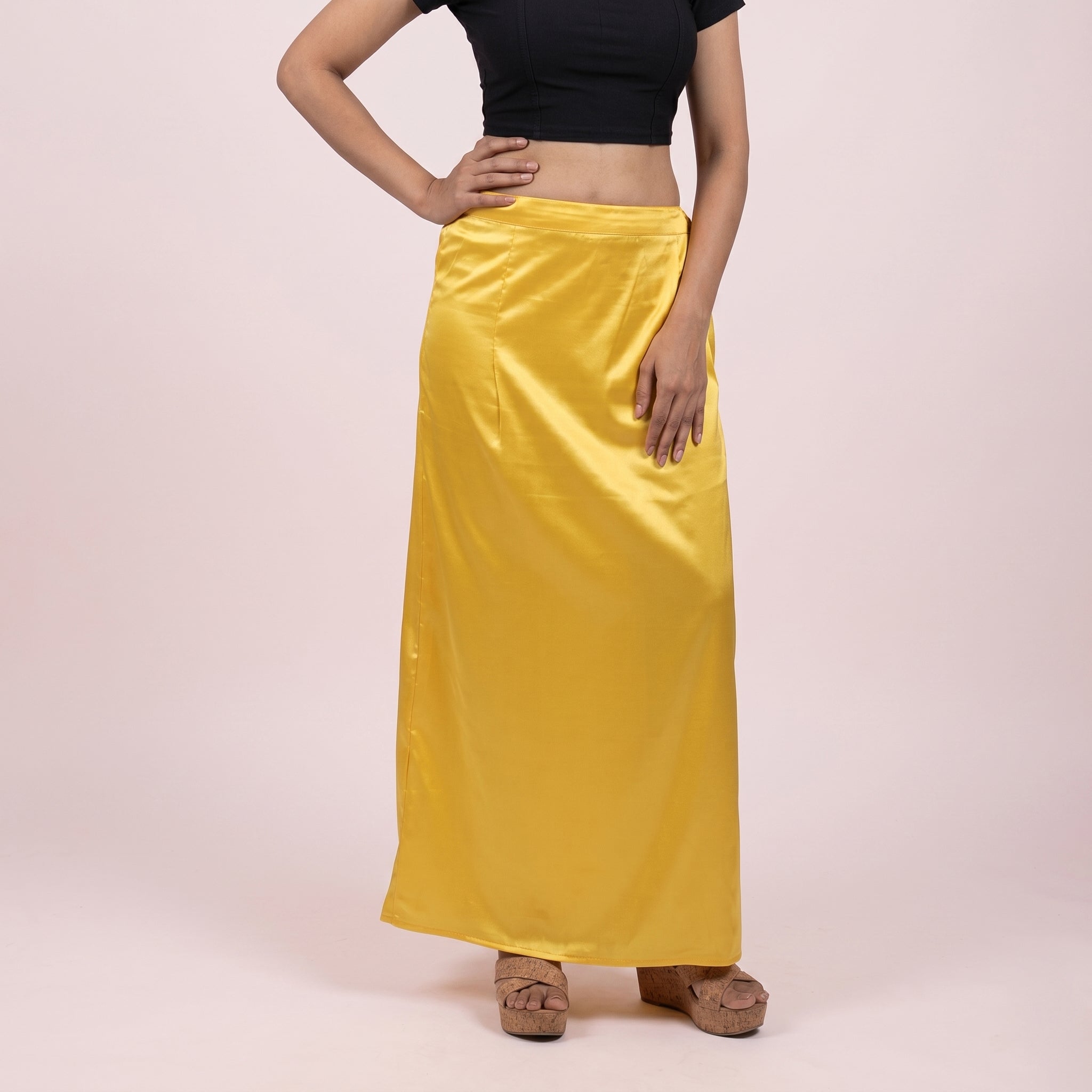 Person wearing a yellow satin skirt on a pink background
