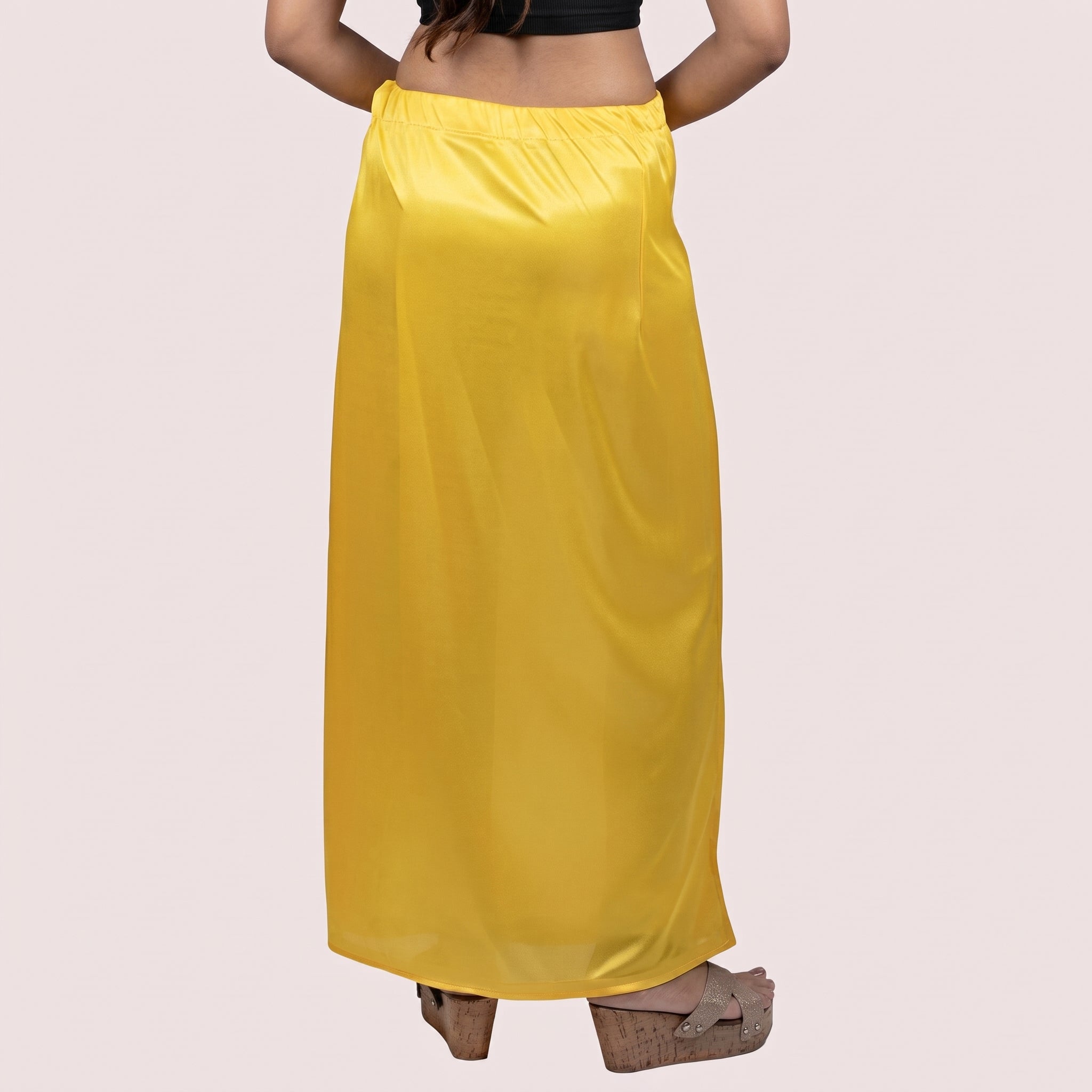Yellow satin skirt worn by a person on a light pink background