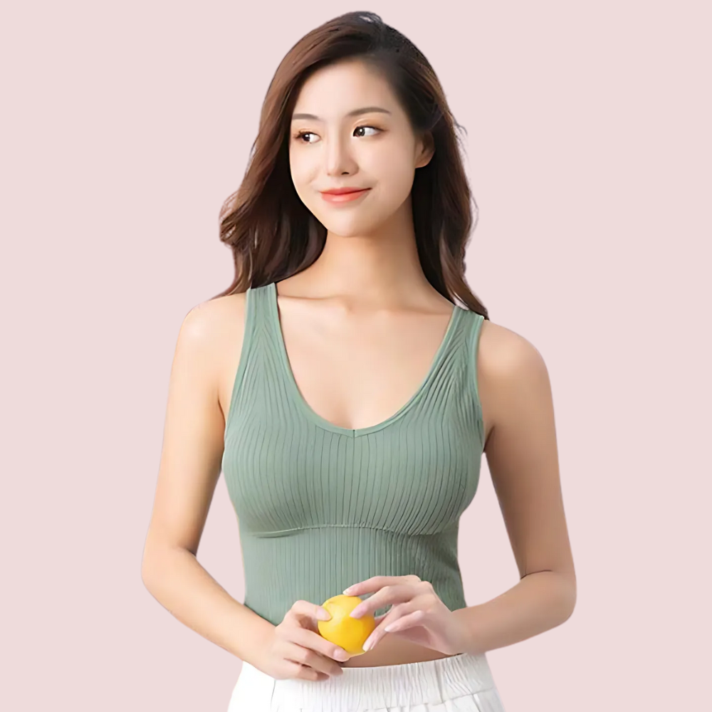 Woman holding a lemon wearing a green tank top against a light pink background
