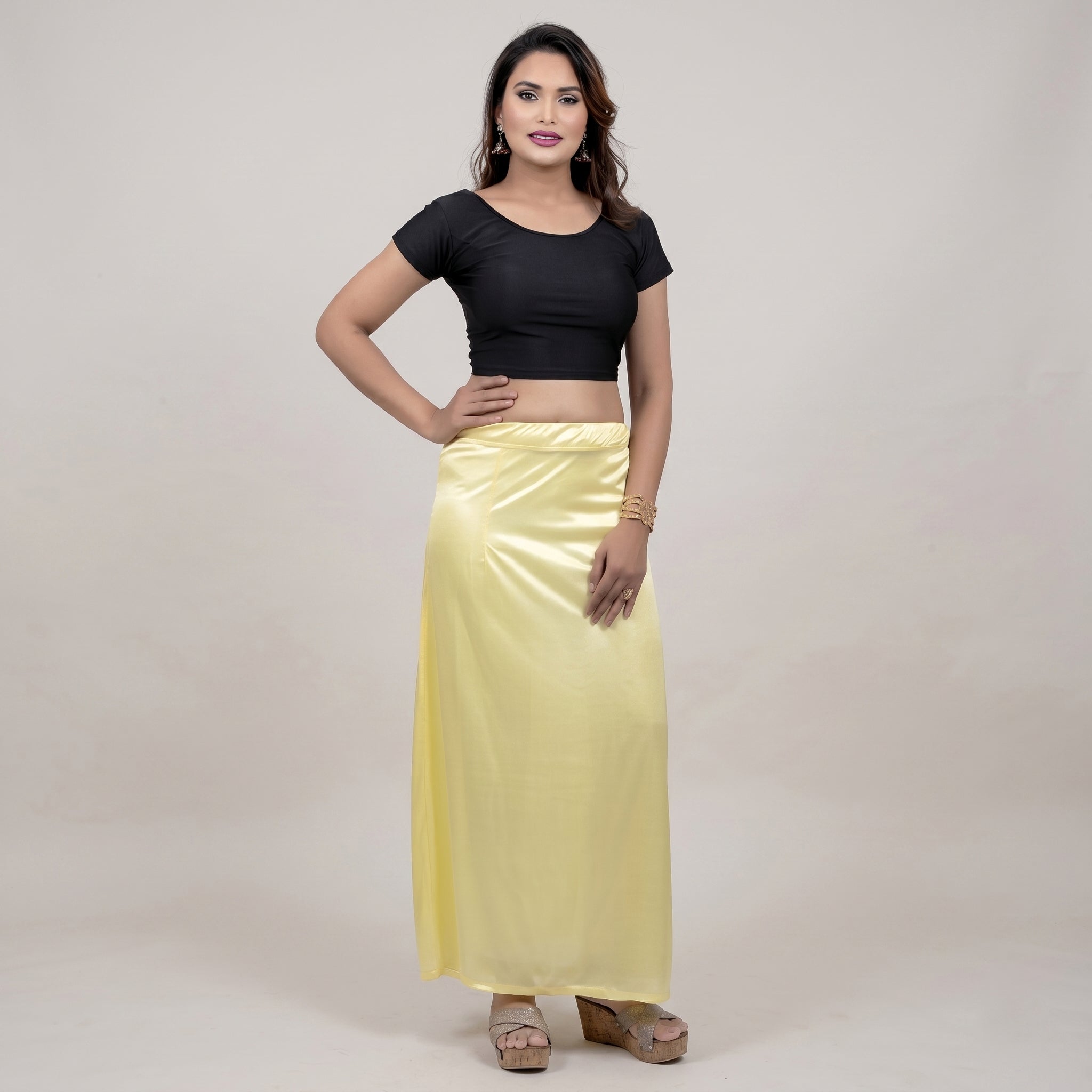 Woman wearing a black top and yellow skirt on a plain background
