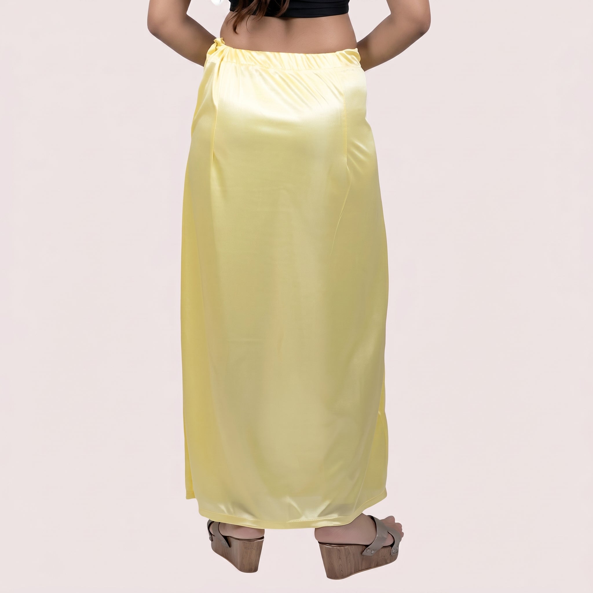 Person wearing a yellow satin skirt on a plain background