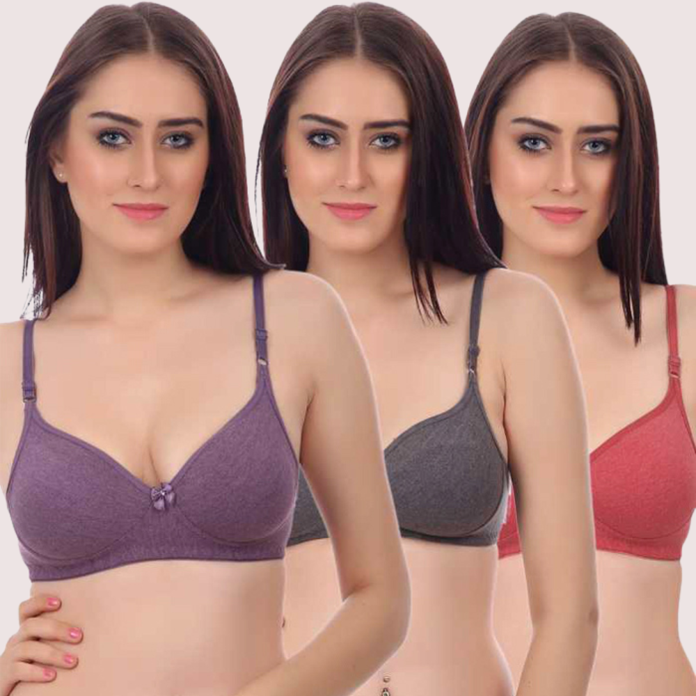 Woman wearing three different colored bras on a plain background
