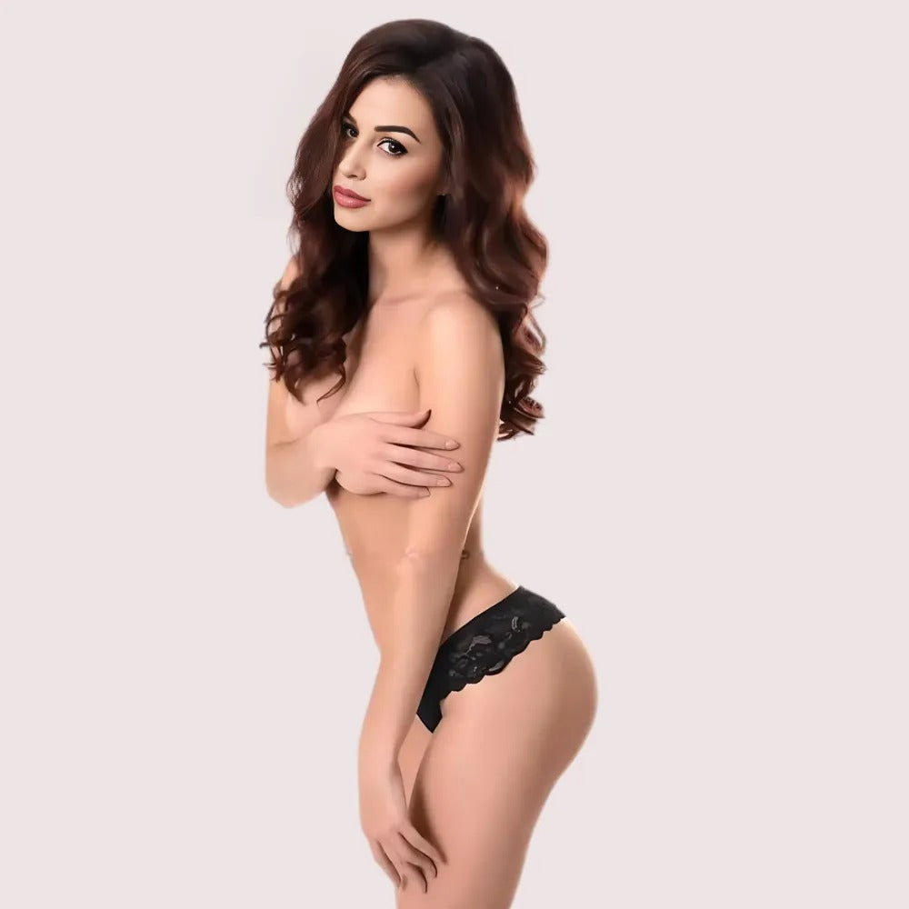 Woman wearing a black lace thong against a plain background