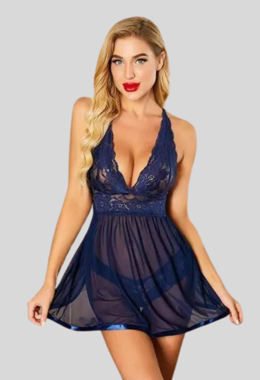 Woman wearing a navy blue lace babydoll dress on a gray background