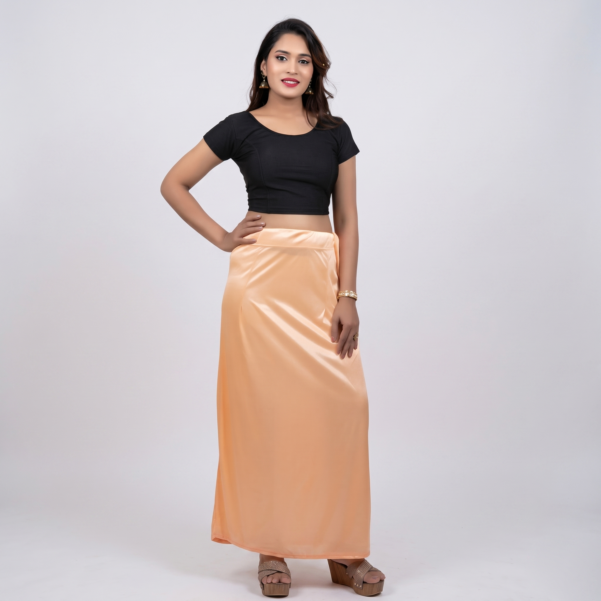 Woman wearing a black top and peach skirt on a white background
