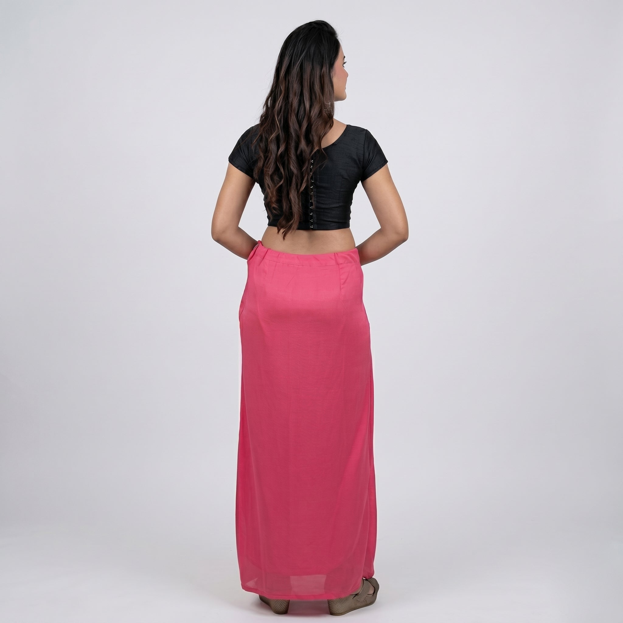 Woman wearing a black top and pink skirt on a white background