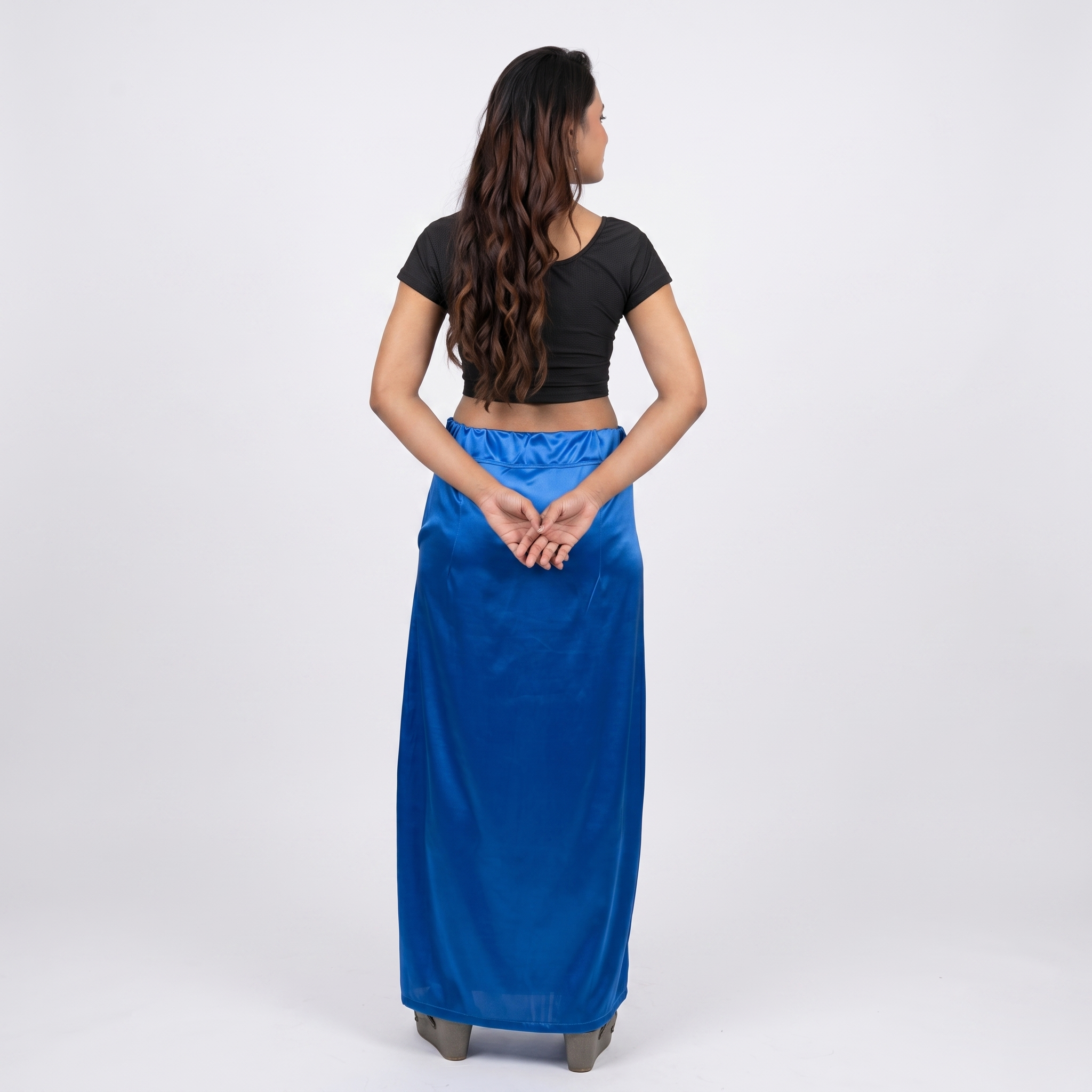 Woman wearing a black top and blue skirt on a white background