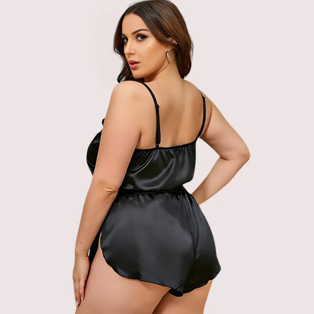 Woman wearing a black satin nightgown against a plain background