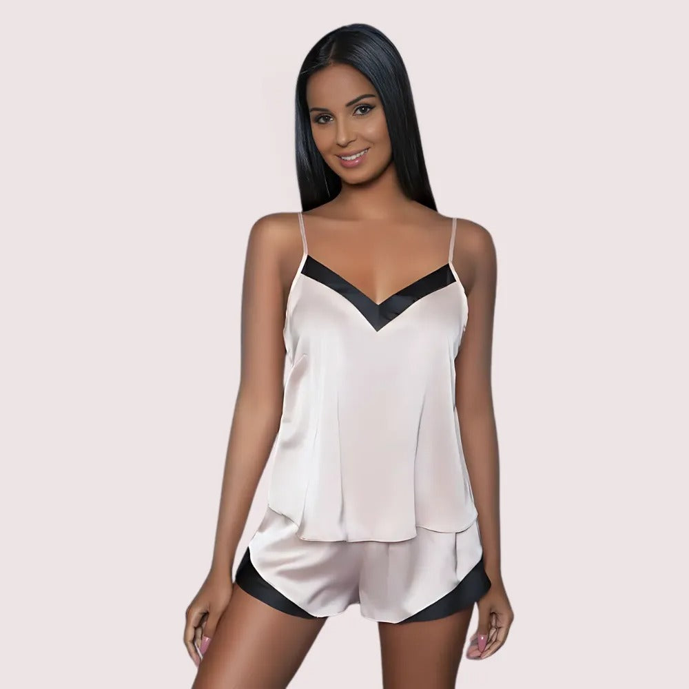 Woman wearing a white and black satin pajama set on a light pink background
