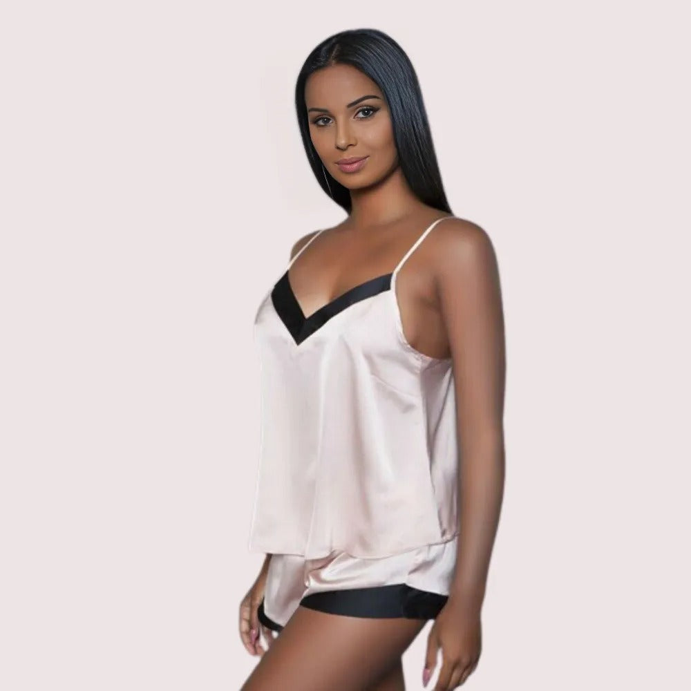 Woman wearing a white and black satin nightgown on a light pink background