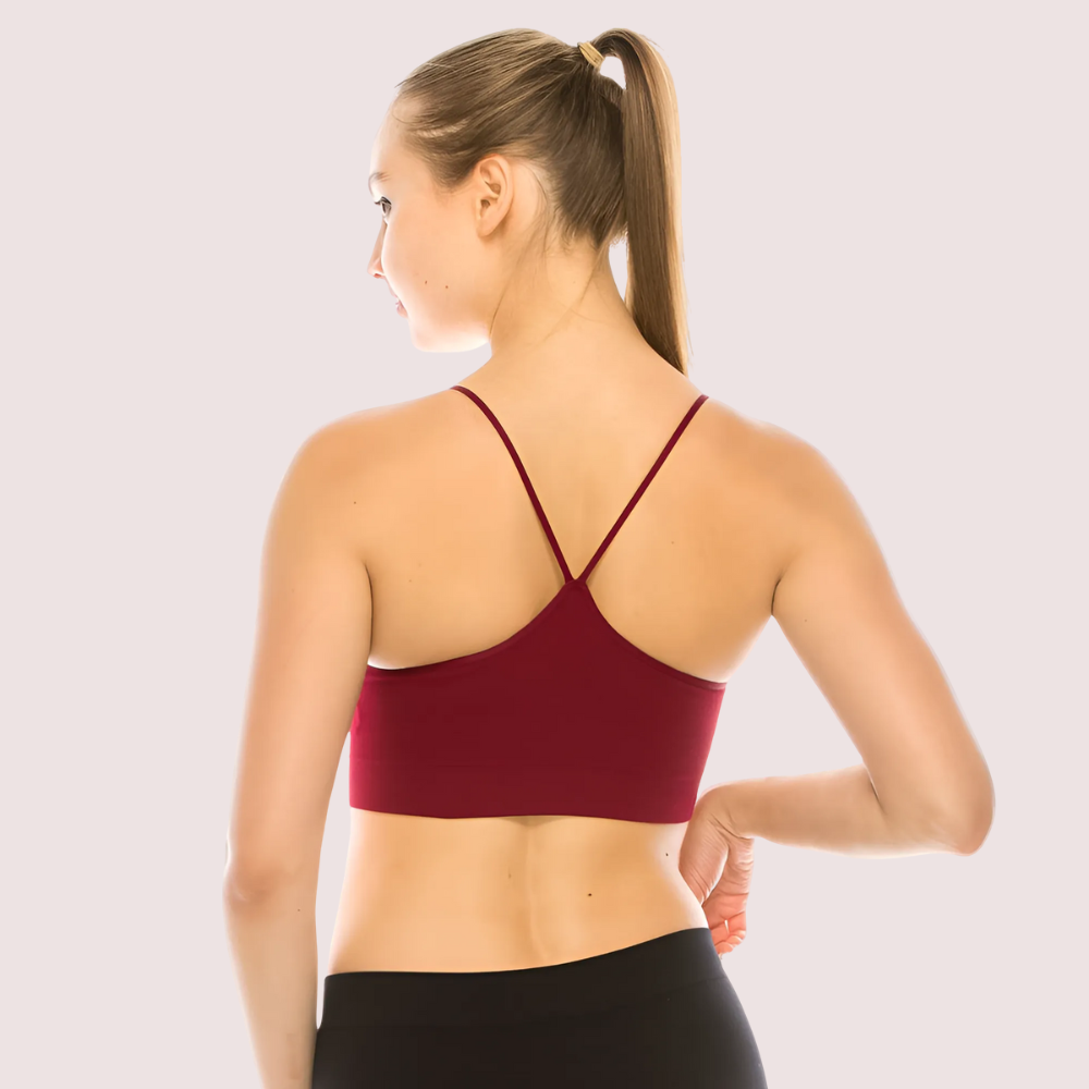 Woman wearing a maroon sports bra and black leggings on a light gray background