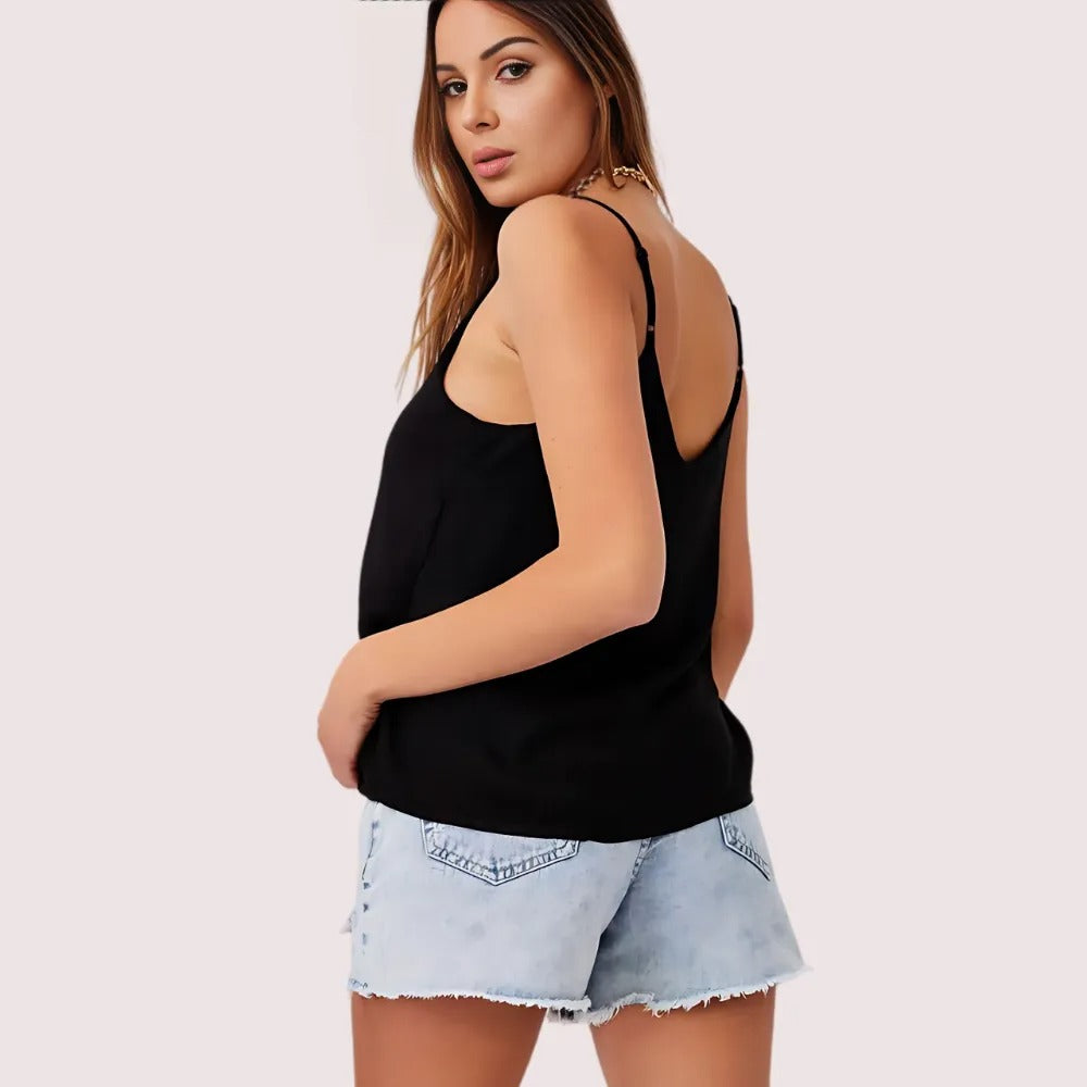 Woman wearing a black tank top and denim shorts on a white background