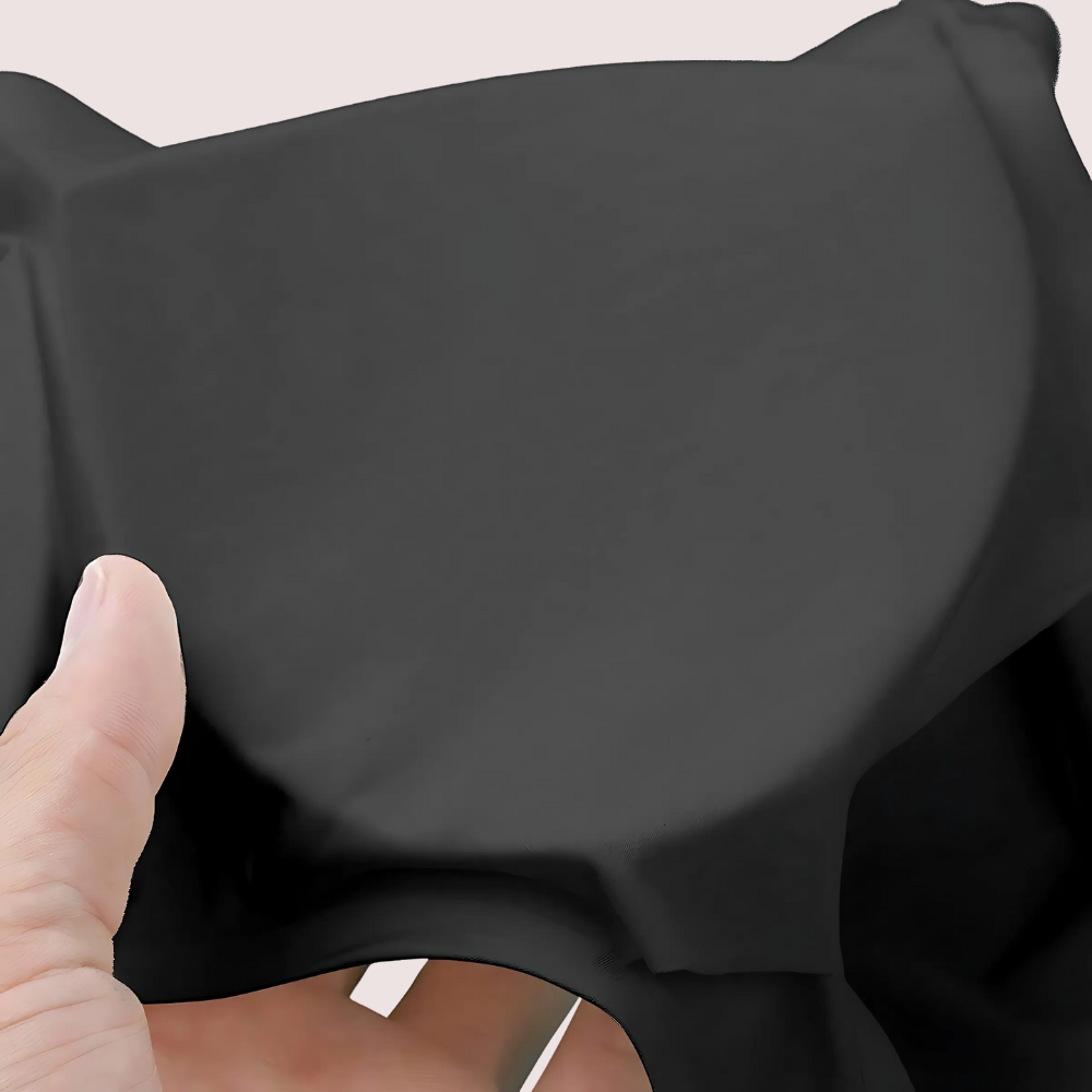 Hand holding a piece of black fabric against a neutral background