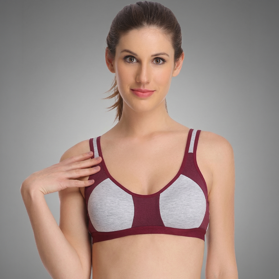 Woman wearing a maroon and gray sports bra against a gray background