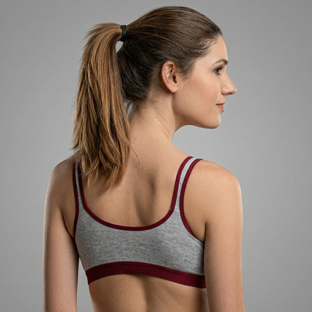 Woman wearing a gray sports bra with red straps on a gray background