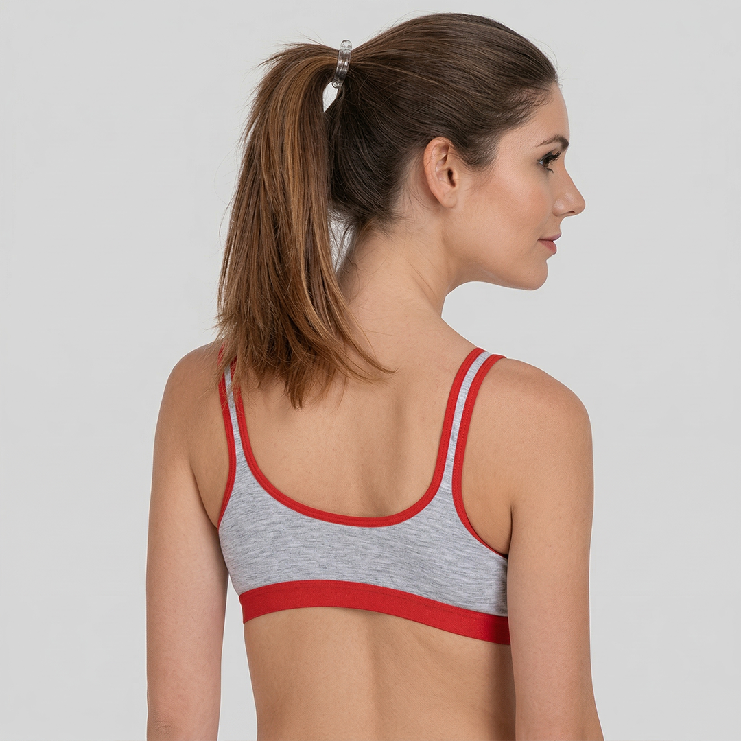 Woman wearing a gray sports bra with red trim on a plain background