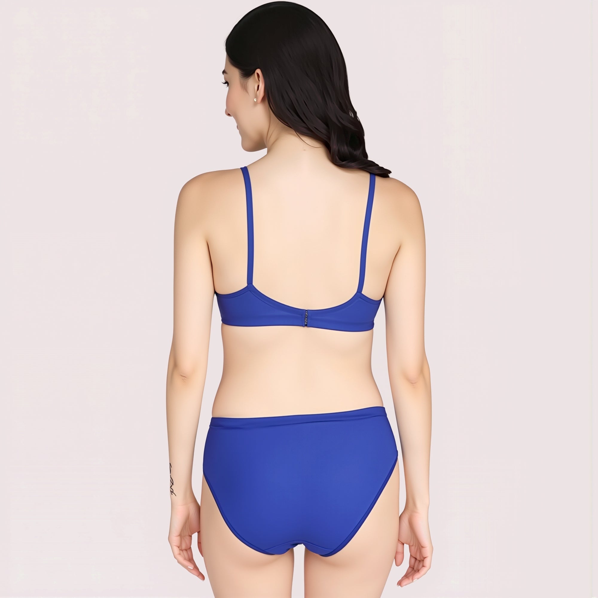 Woman wearing a blue bikini set on a light pink background