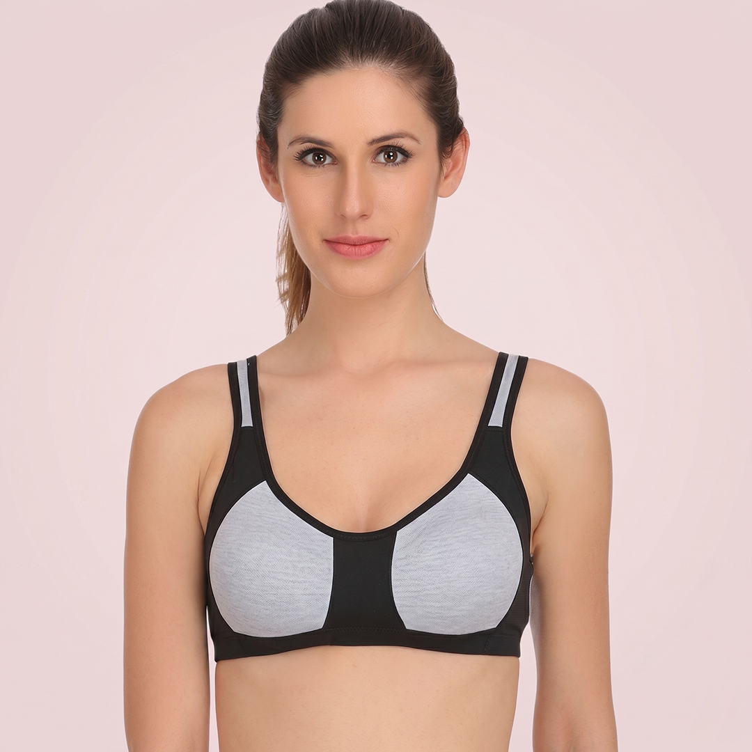 Woman wearing a black and gray bralette against a pink background