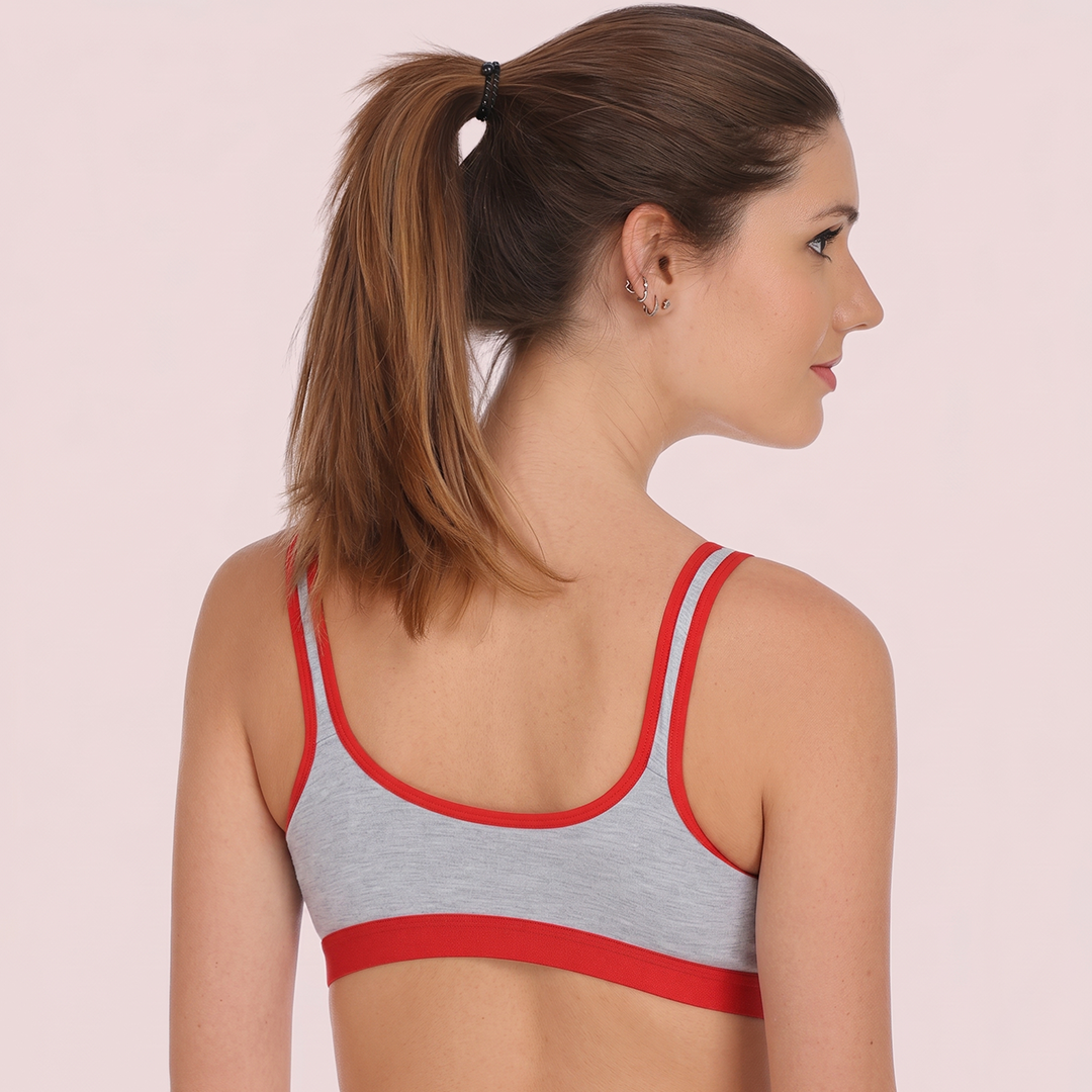 Woman wearing a gray and red sports bra on a light pink background