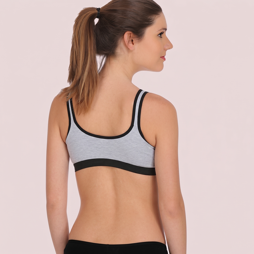 Woman wearing a gray sports bra with black accents on a light pink background