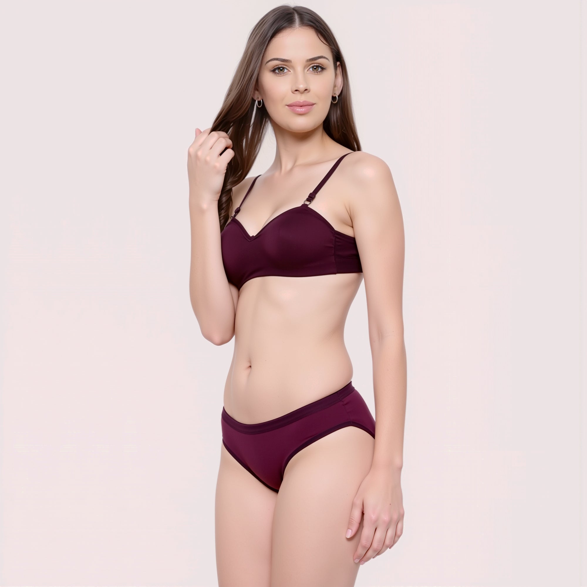 Woman wearing a burgundy bikini set on a light pink background