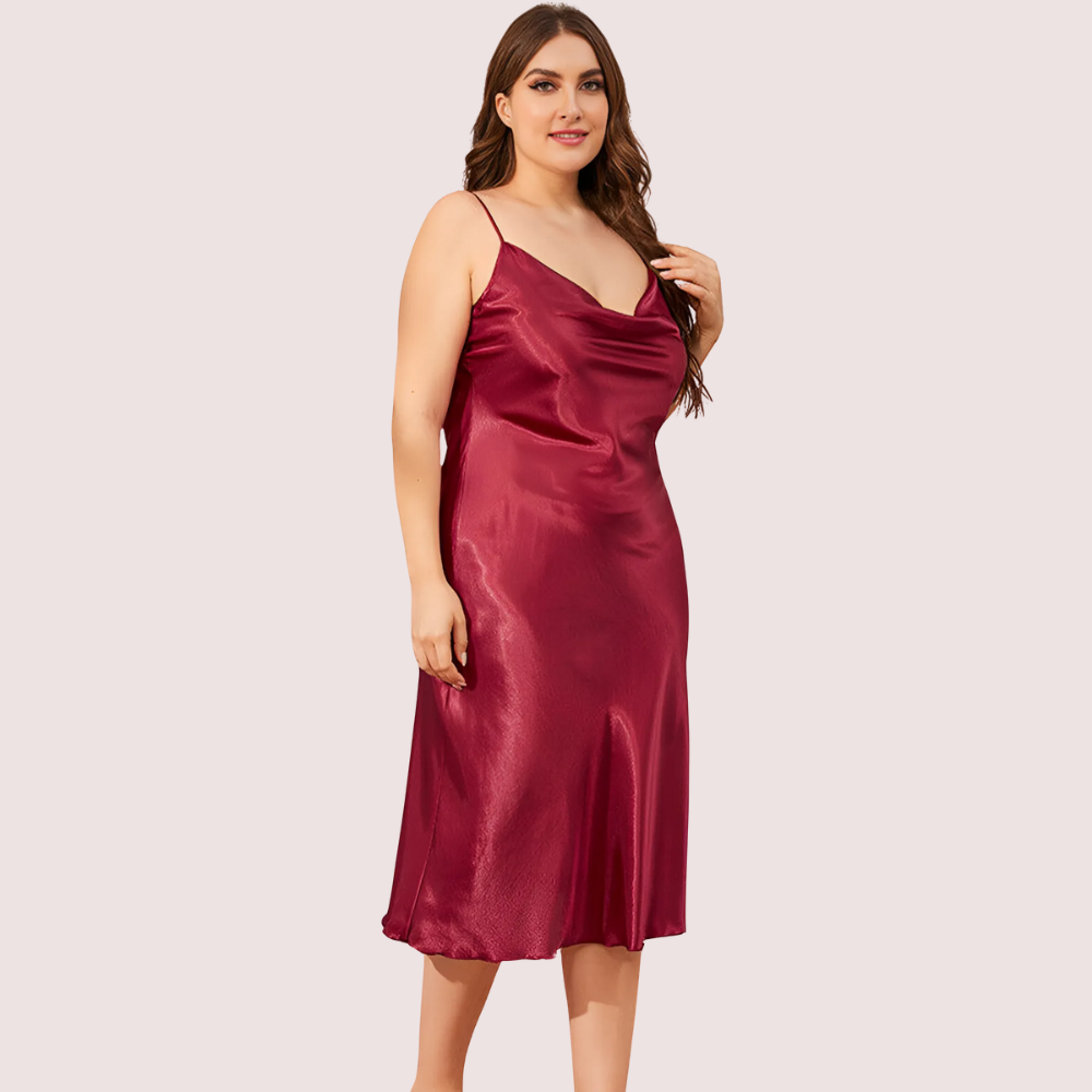 Woman wearing a burgundy satin slip dress on a light pink background
