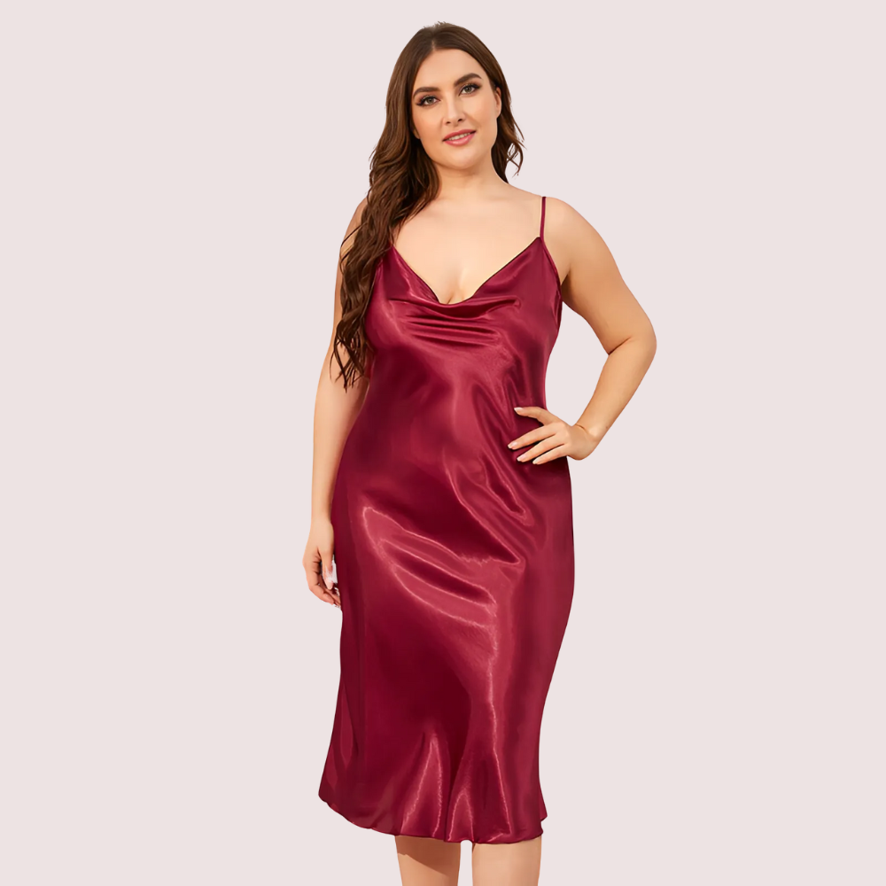 Woman wearing a burgundy satin slip dress on a light pink background
