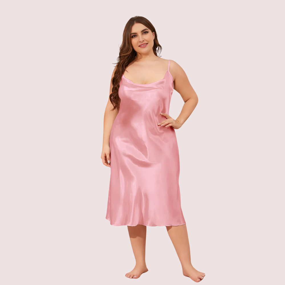 Woman wearing a pink satin slip dress against a plain background
