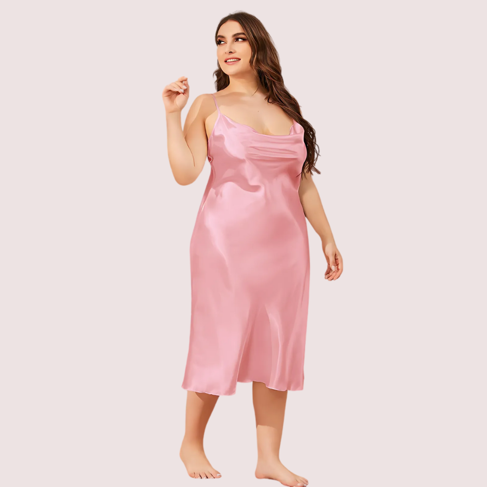 Woman wearing a pink satin slip dress on a plain background