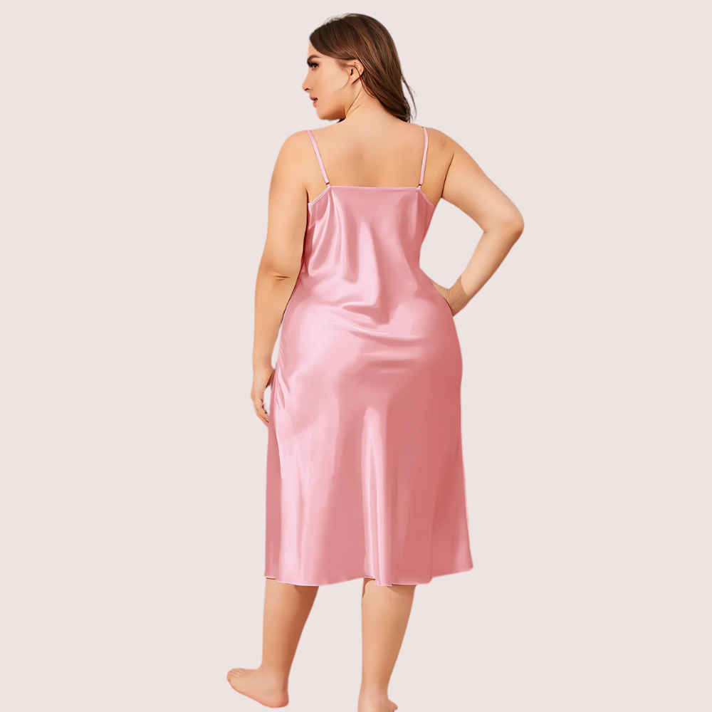 Woman wearing a pink satin slip dress against a plain background