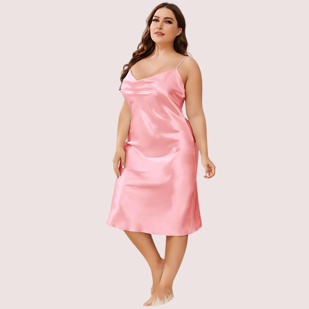 Woman wearing a pink satin slip dress on a plain background