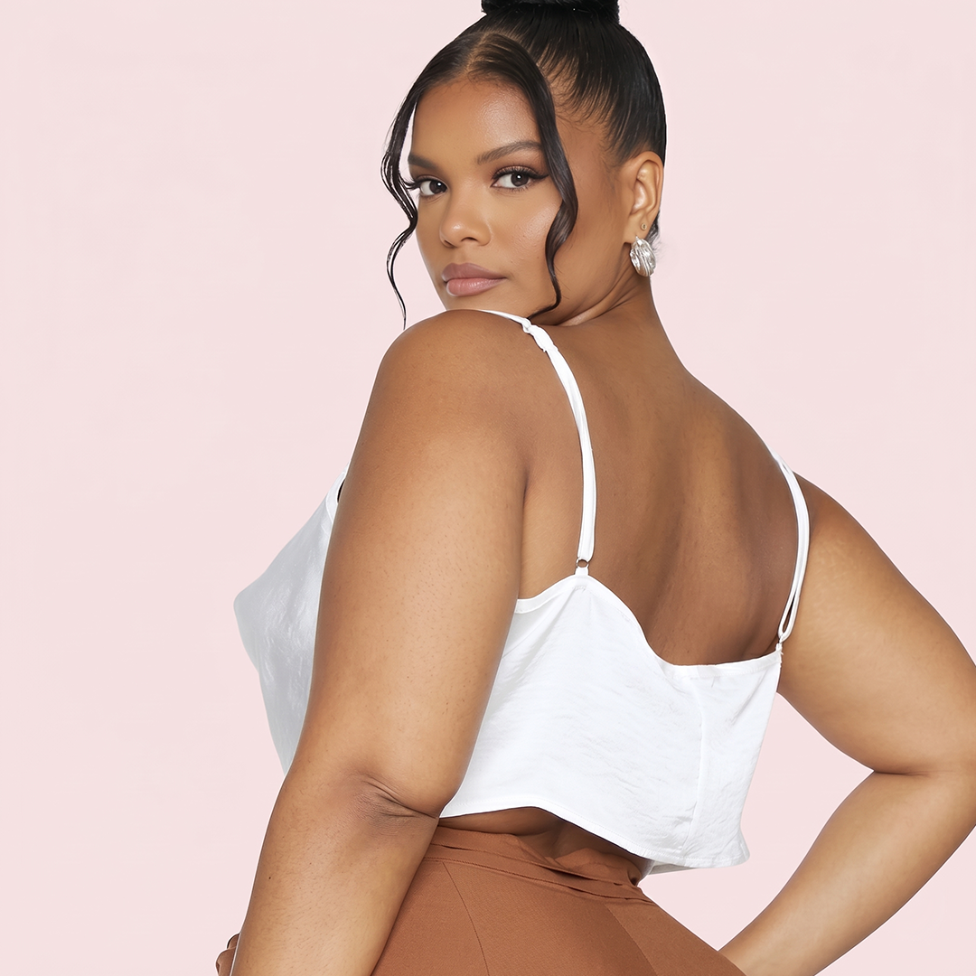 Woman wearing a white top with thin straps on a pink background