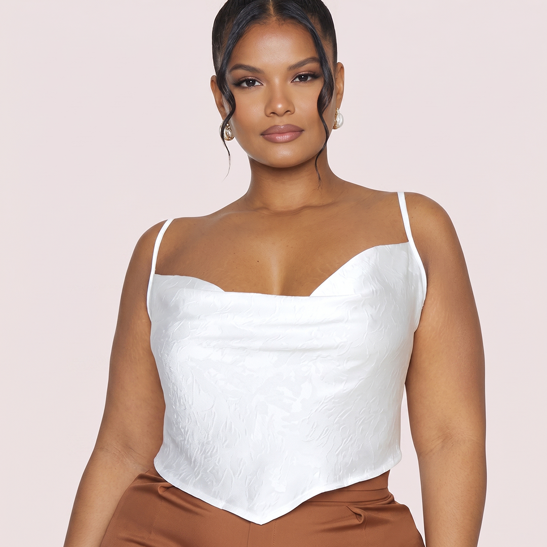 Woman wearing a white top and brown pants against a light pink background