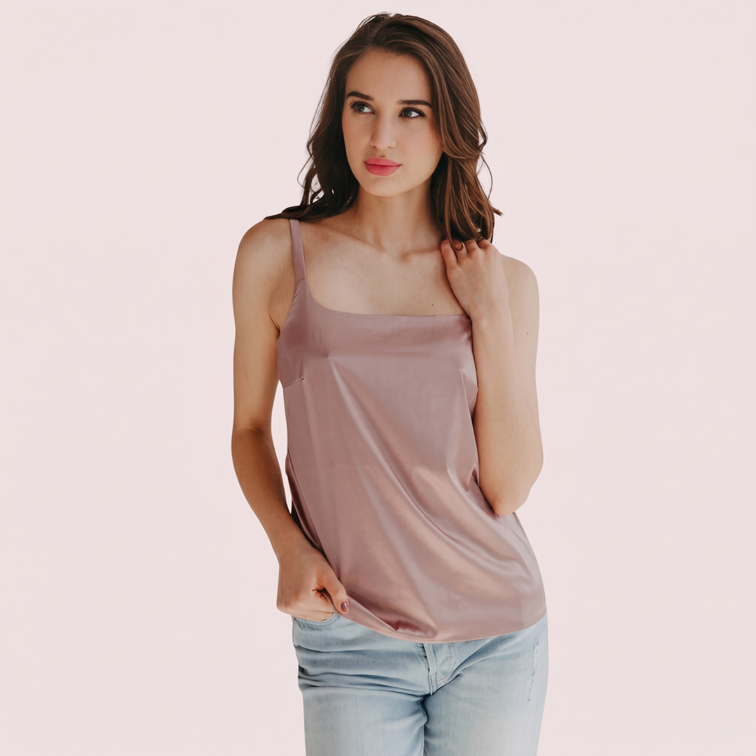 Woman wearing a pink tank top and light blue jeans on a plain background