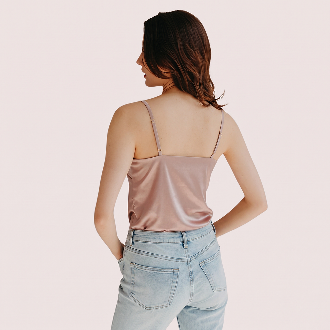Woman wearing a beige top and light blue jeans on a plain background