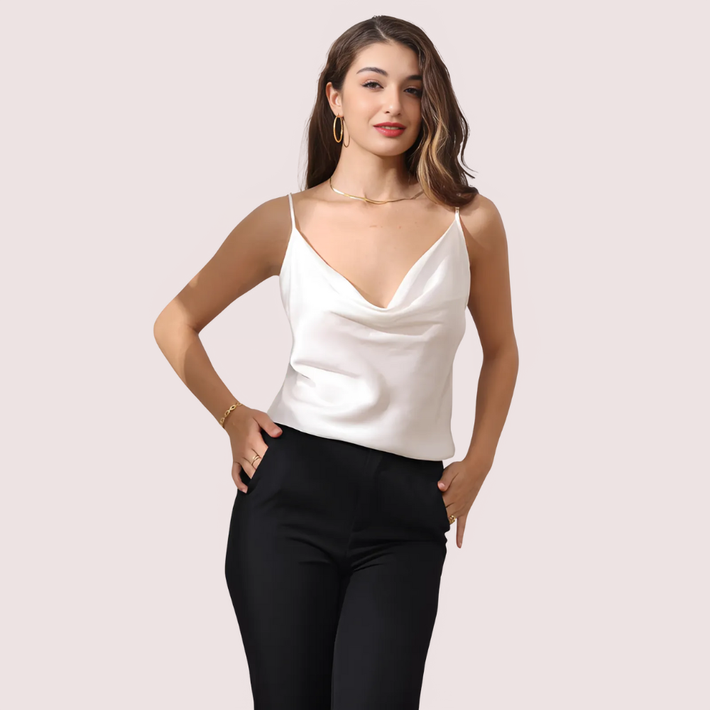 Woman wearing a white top and black pants on a light pink background