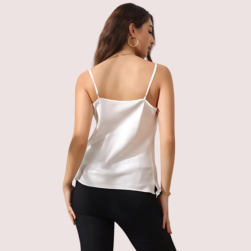 Woman wearing a white satin camisole against a plain background