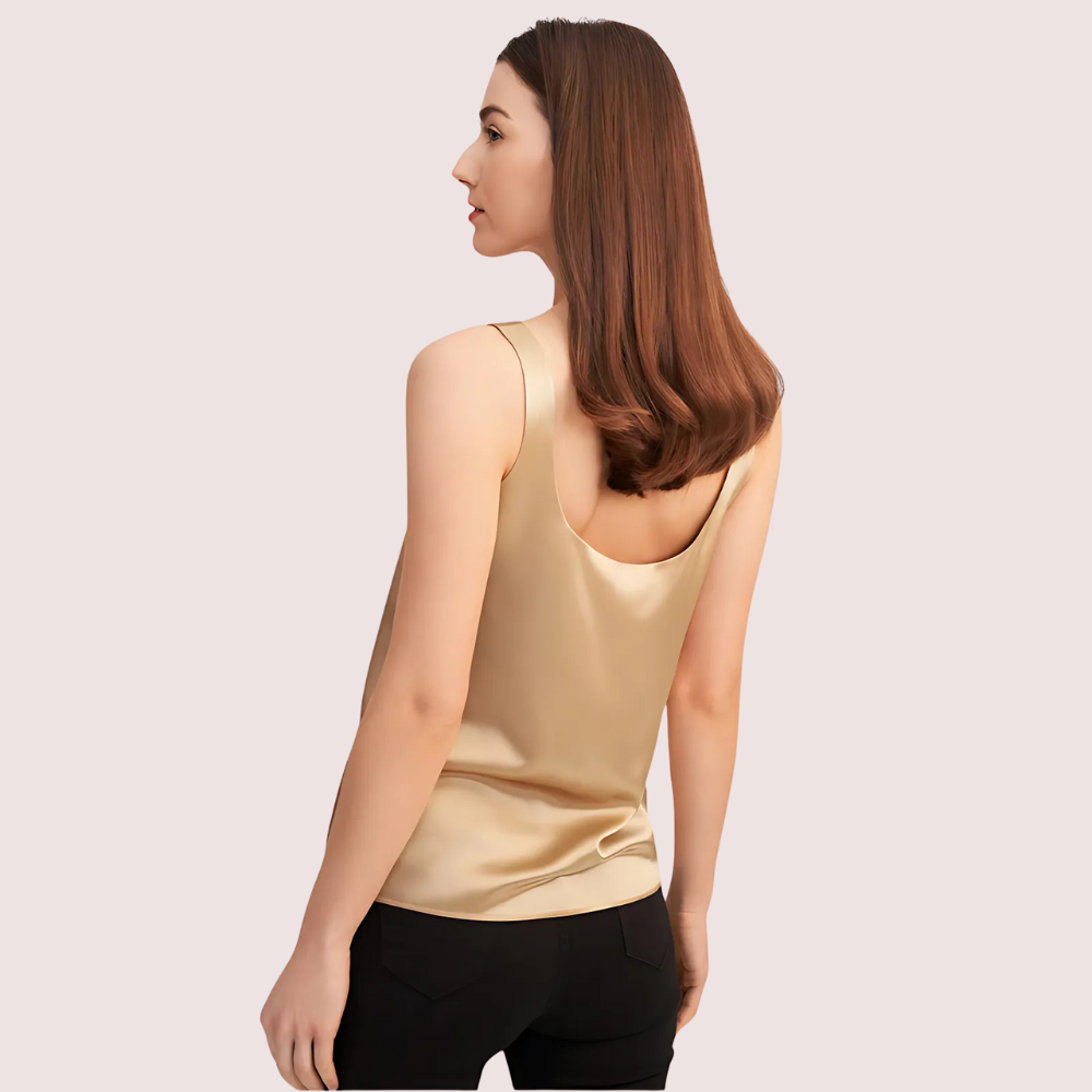 Woman wearing a gold tank top on a light pink background