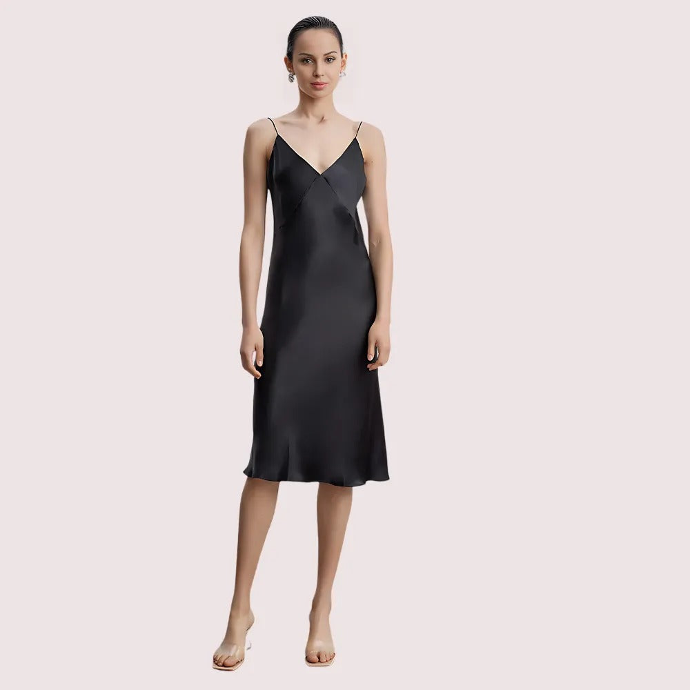 Woman wearing a black slip dress on a light pink background